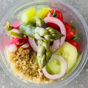 Bol de quinoa aux asperges, tomates cerises, oignon rouge et radis pour un repas sain et coloré.